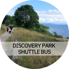 Discovery Park Shuttle Bus - Photo: A couple walking down a path in Discovery Park with trees and the water in view.
