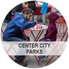 Center City Parks - Photo: An older man showing a child how to play checkers at a city park