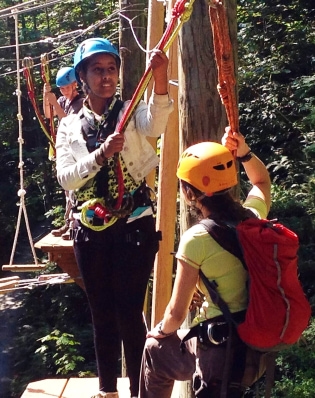 Teens on a zipline rope in a forest during a nature day camp