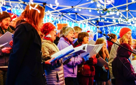 A group of carolers singing in a tent at Pathway of Lights in Green Lake