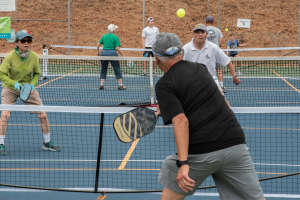 adults playing pickleball on a blue court