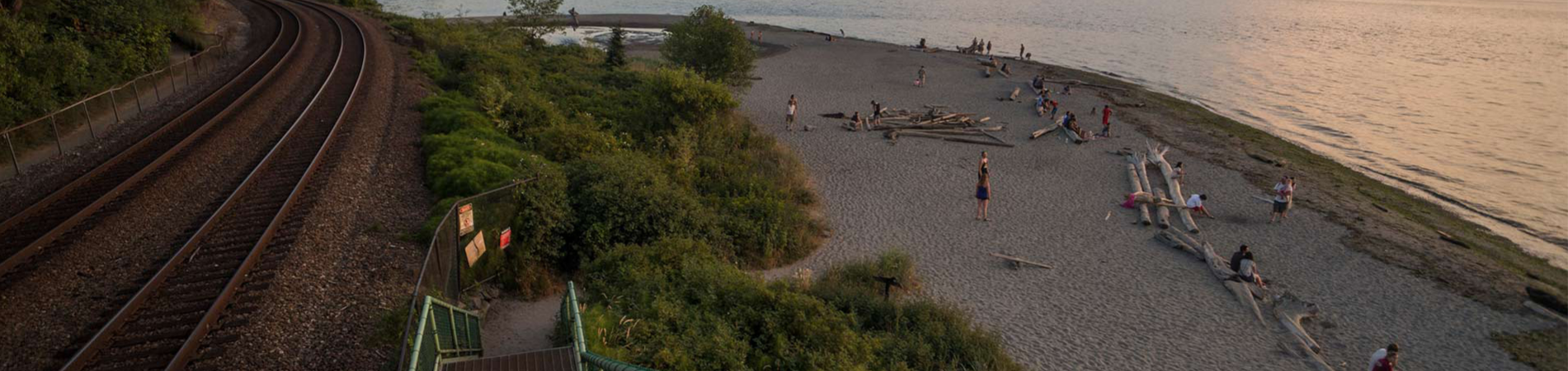wide shot of carkeek park at sunset: with train tracks on the left and the beach on the right