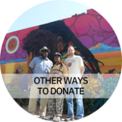 Other Ways to Donate - Photo: Three people smiling outside of a building with a large mural.