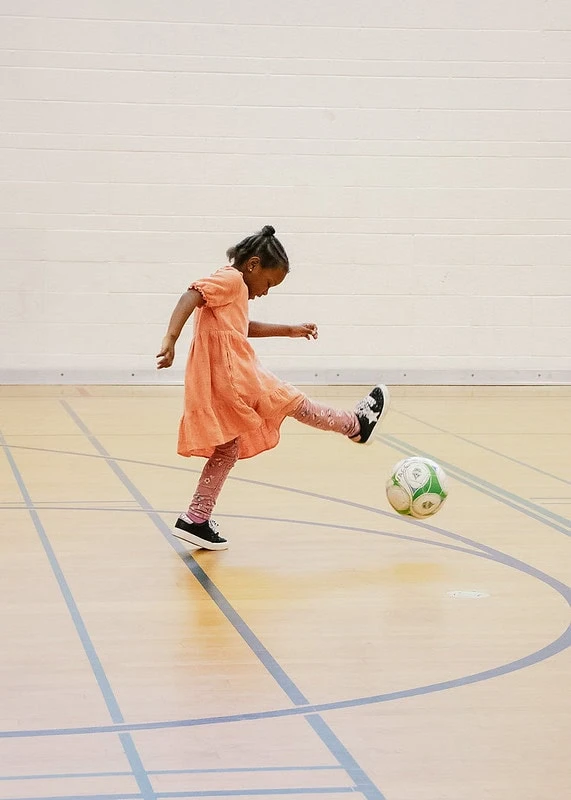 Girl playing with a soccer ball in a gym