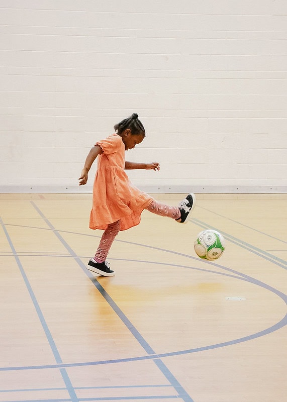 Girl playing with a soccer ball in a gym